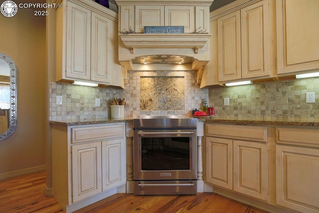 kitchen with light stone counters, cream cabinetry, stainless steel range with electric stovetop, and decorative backsplash