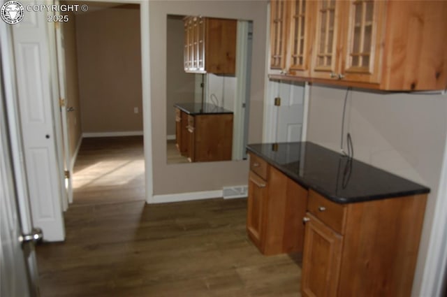 kitchen featuring brown cabinetry, dark wood-style flooring, and baseboards