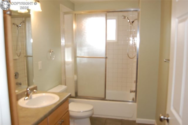 full bathroom with toilet, tile patterned floors, vanity, and shower / bath combination with glass door