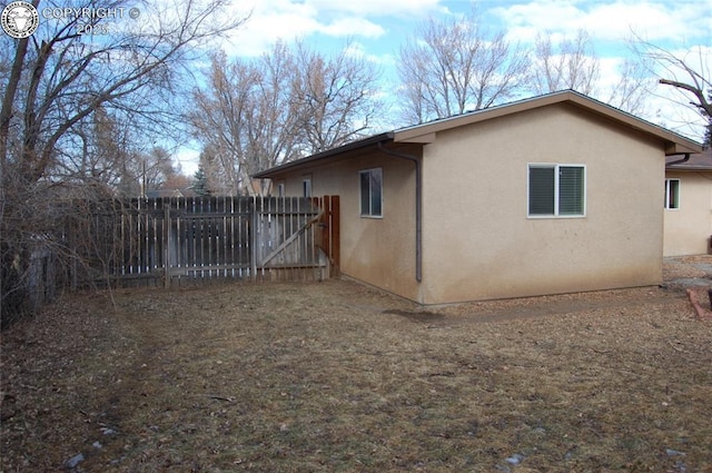 view of side of property with fence and stucco siding