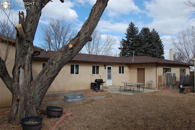 rear view of house with a patio area, a chimney, and stucco siding