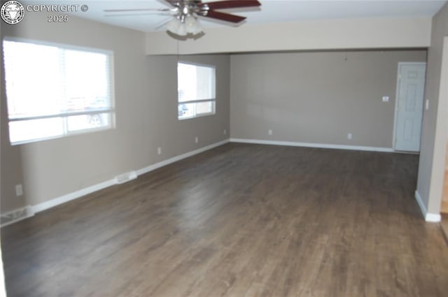 spare room featuring dark wood-style floors, ceiling fan, visible vents, and baseboards