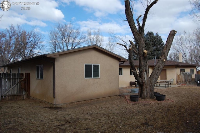 view of side of property with fence and stucco siding