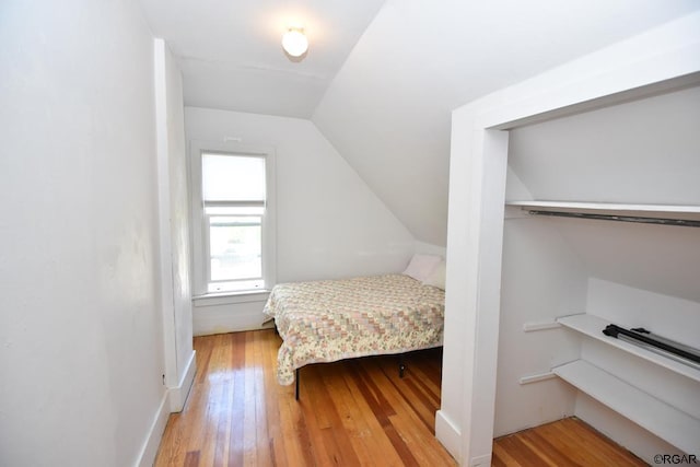 bedroom with vaulted ceiling, a closet, and light hardwood / wood-style flooring