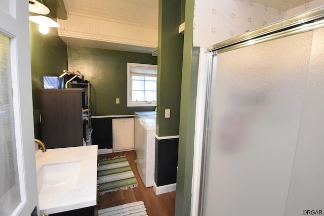 bathroom with hardwood / wood-style flooring, washing machine and clothes dryer, and vanity