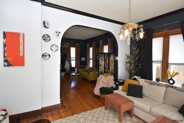 living room with an inviting chandelier, wood-type flooring, ornamental molding, and a textured ceiling