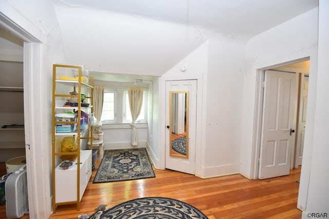 hall featuring vaulted ceiling and light hardwood / wood-style flooring