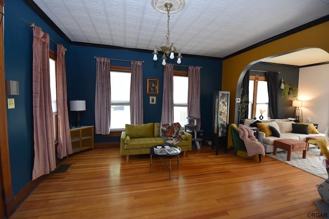 living room featuring crown molding, plenty of natural light, hardwood / wood-style floors, and a chandelier