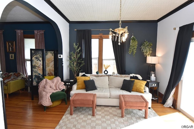 living room with ornamental molding, a notable chandelier, and light hardwood / wood-style floors