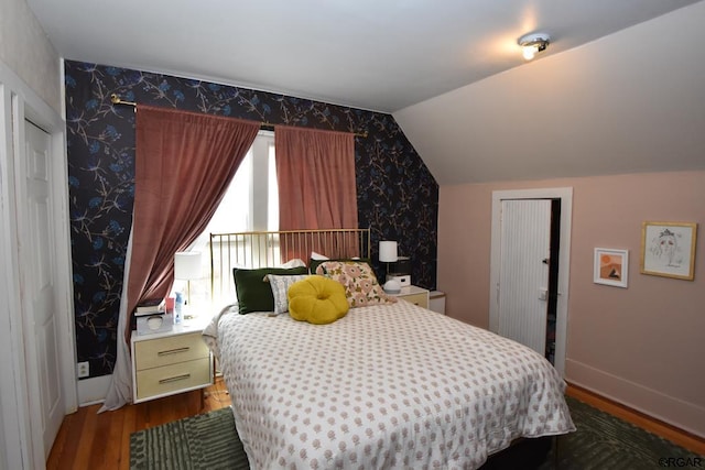 bedroom with multiple windows, wood-type flooring, and vaulted ceiling