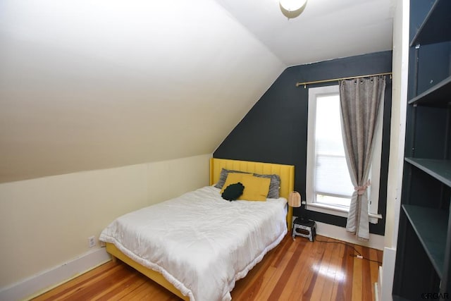 bedroom with multiple windows, hardwood / wood-style floors, and vaulted ceiling