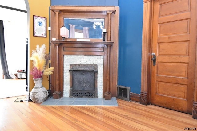 living room with a tiled fireplace and wood-type flooring