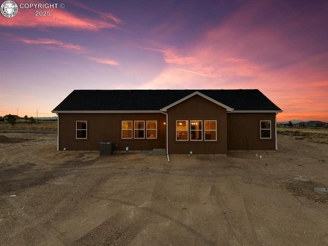 back house at dusk featuring central AC