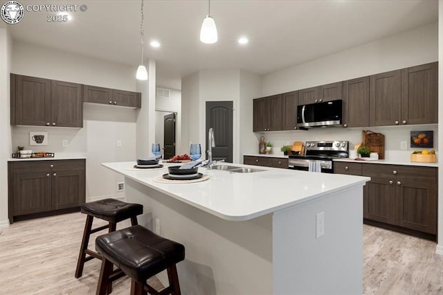 kitchen with appliances with stainless steel finishes, a kitchen island with sink, a breakfast bar area, and sink