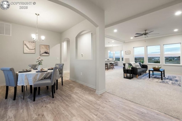 dining room featuring ceiling fan with notable chandelier and light hardwood / wood-style flooring