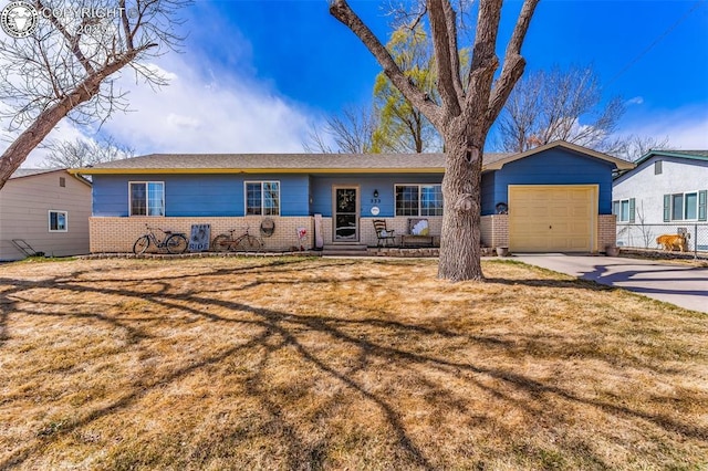 single story home featuring brick siding, an attached garage, a front yard, and concrete driveway