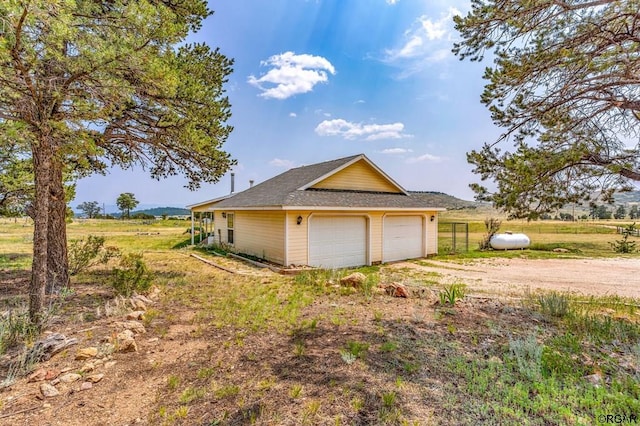 view of home's exterior featuring a garage and a rural view