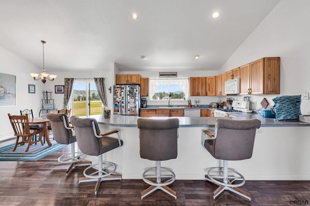 kitchen with pendant lighting, white appliances, lofted ceiling, and a kitchen breakfast bar