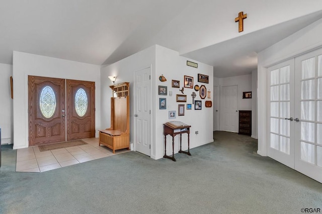 foyer entrance featuring vaulted ceiling, light carpet, and french doors