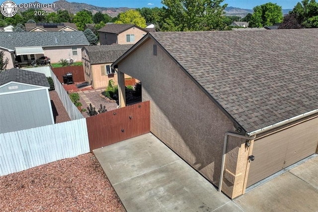 355 Antero Dr, Canon City, CO 81212 - view of home's exterior featuring a storage shed, a mountain view, roof with shingles, stucco siding, and a gate