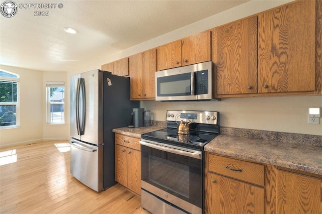 355 Antero Dr, Canon City, CO 81212 - kitchen featuring appliances with stainless steel finishes, brown cabinets, light wood-style flooring, dark countertops, and recessed lighting