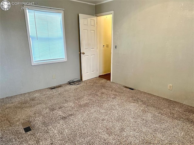 unfurnished room with visible vents and carpet flooring