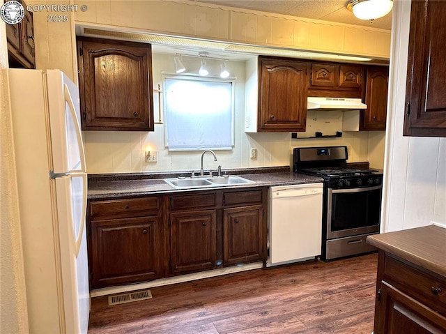 kitchen with under cabinet range hood, white appliances, a sink, visible vents, and dark countertops