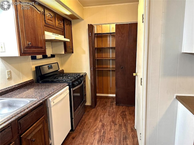 kitchen featuring dark countertops, dark wood-style floors, gas range, white dishwasher, and under cabinet range hood