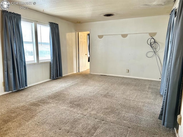 spare room featuring carpet floors, visible vents, and baseboards