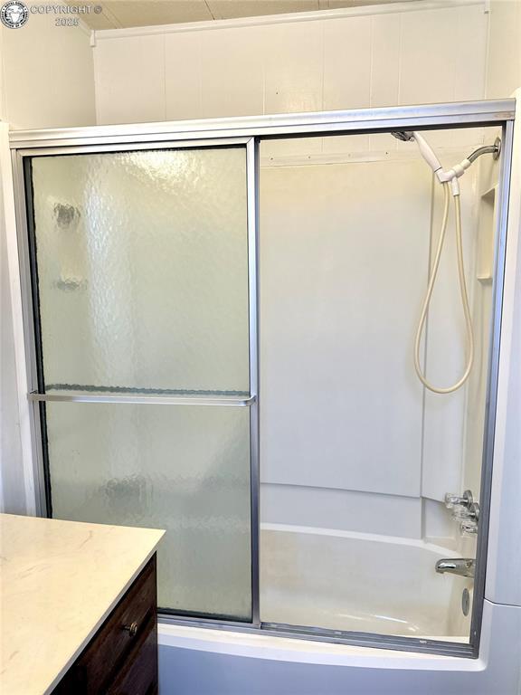 full bath featuring combined bath / shower with glass door and vanity