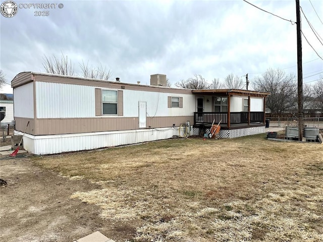 back of property featuring a wooden deck, cooling unit, and a yard