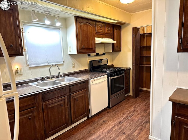 kitchen featuring white dishwasher, under cabinet range hood, a sink, dark countertops, and stainless steel range with gas stovetop