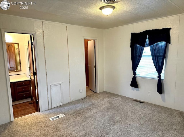 bedroom with visible vents, light carpet, and ensuite bath