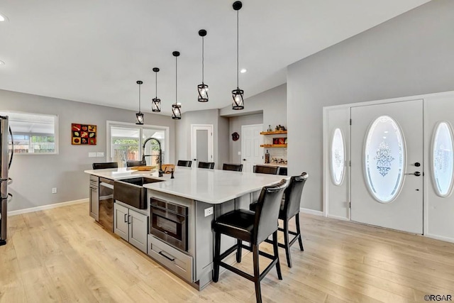 kitchen with appliances with stainless steel finishes, a breakfast bar, sink, hanging light fixtures, and a center island with sink