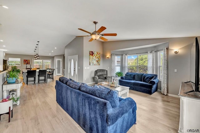 living room with a wealth of natural light, vaulted ceiling, and light wood-type flooring