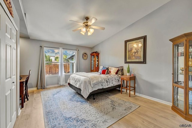 bedroom featuring light hardwood / wood-style floors, lofted ceiling, ceiling fan, and a closet