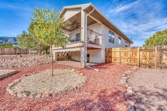 view of side of property featuring a mountain view, a balcony, and ceiling fan