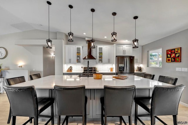 kitchen with hanging light fixtures, stainless steel refrigerator with ice dispenser, white cabinets, and a kitchen bar