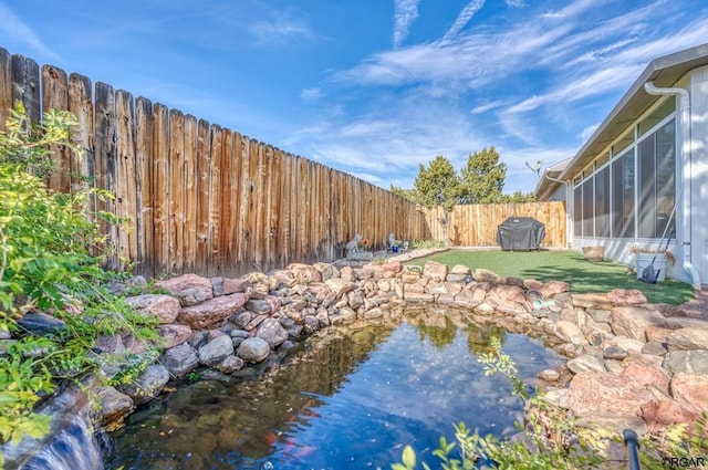 view of yard featuring a garden pond and a sunroom