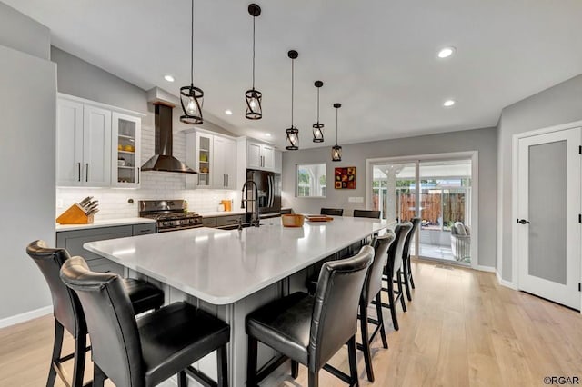 kitchen featuring pendant lighting, a breakfast bar, a spacious island, stainless steel gas range oven, and wall chimney exhaust hood