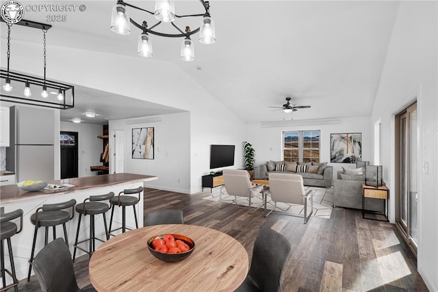 dining room featuring dark wood-type flooring, lofted ceiling, and ceiling fan with notable chandelier