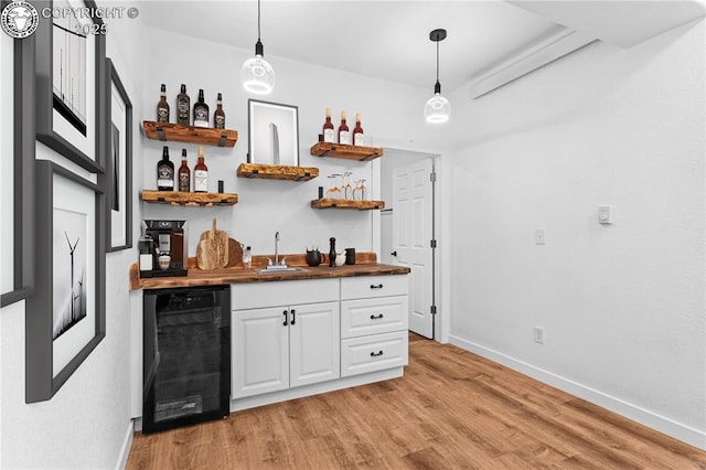 bar featuring sink, white cabinetry, hanging light fixtures, wine cooler, and light wood-type flooring