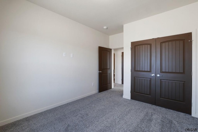 unfurnished bedroom featuring dark colored carpet and a closet