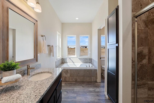 full bathroom with vanity, hardwood / wood-style floors, shower with separate bathtub, and toilet