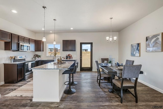 kitchen featuring stainless steel appliances, a center island, pendant lighting, and dark brown cabinetry