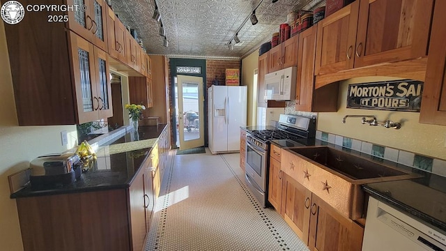 120 E Main St, Florence, CO 81226 - kitchen with dark countertops, a sink, brown cabinetry, and white appliances
