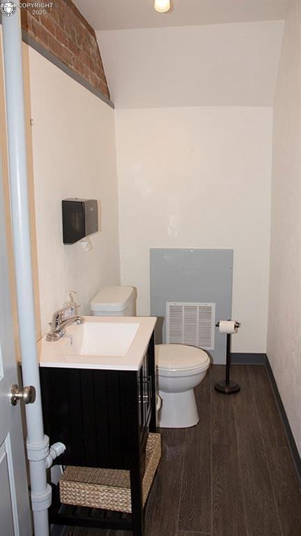 120 E Main St, Florence, CO 81226 - half bath with wood finished floors, vaulted ceiling, toilet, vanity, and visible vents