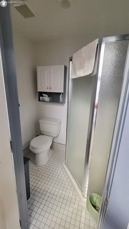 120 E Main St, Florence, CO 81226 - bathroom featuring toilet, tile patterned flooring, visible vents, and a shower stall
