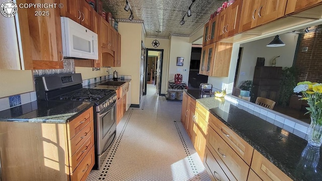 120 E Main St, Florence, CO 81226 - kitchen featuring dark stone counters, glass insert cabinets, an ornate ceiling, white microwave, and stainless steel gas range oven