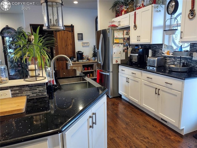 kitchen featuring decorative backsplash, a sink, freestanding refrigerator, and white cabinets